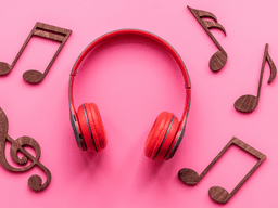 Red headphones surrounded by wooden music notes on a pink background